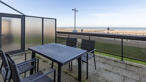 A balcony with a table and chairs overlooking a beach. - Attractive Studio With a Sea-view (Middelkerke)