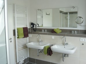 A bathroom with two sinks, a mirror, and a towel rack.