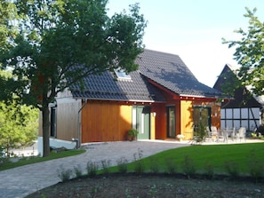 A traditional house with a sloped roof, wooden exterior, and a front porch with outdoor seating.