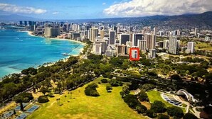 An aerial view of a coastal city with high-rise buildings, a beach, and a park area.