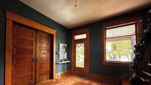 Une pièce aux murs sombres, avec des portes en bois, une grande fenêtre et un tapis à motifs.
