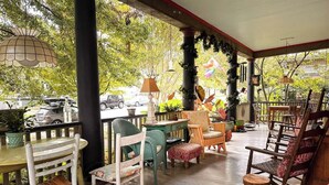 Une terrasse extérieure aménagée avec du mobilier en bois, notamment des chaises et des tables, entourée de verdure et d’éléments décoratifs.