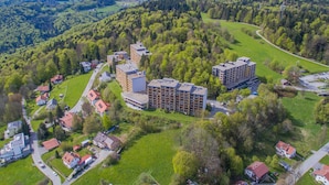 An aerial view of a residential area with multiple apartment buildings, surrounded by lush greenery and a winding road. - Appartement Serges mit Pool und Sauna in Freyung (Freyung)
