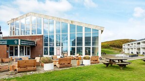 A modern building with large windows, outdoor seating, and a chess table.
