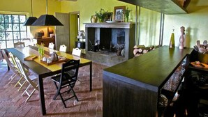 A spacious kitchen with a central island, a dining area with chairs, and a fireplace. - Villa With Pool in Sarteano (Chianciano Terme)