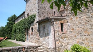 A stone building with a large window and a door, surrounded by greenery. - Villa With Pool in Sarteano (Chianciano Terme)
