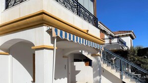 A building with a white facade, a balcony with black railings, and a staircase leading to an upper level.