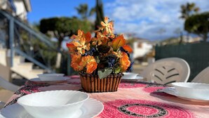 A table set with white plates and a basket of artificial flowers.