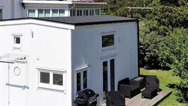 En moderne toetagers bygning med en terrasse og udendørs siddepladser.