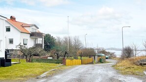 En boligvej med huse, en støvet sti og et vandområde i det fjerne.