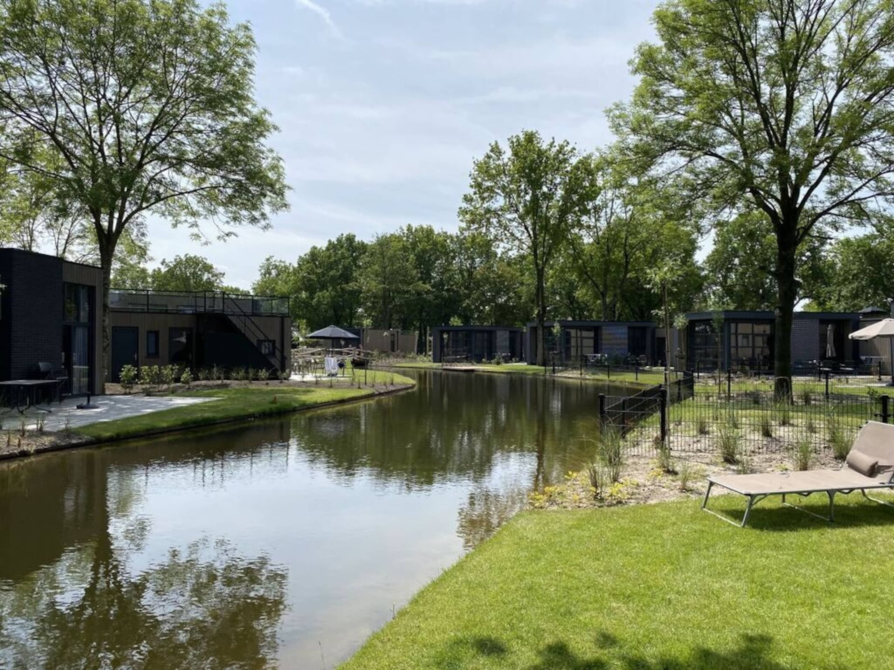 A tranquil outdoor area with a pond, seating, and modern buildings.