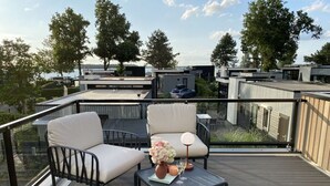 A deck with two chairs and a table, overlooking a residential area with modern buildings and trees. - Cube Elite Noteboom 11 (Hulshorst)