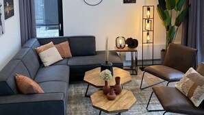 A modern living room with a sectional sofa, two armchairs, a coffee table, and a floor lamp. - Cube Elite Noteboom 11 (Hulshorst)