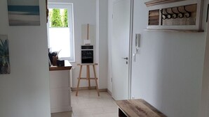 A hallway with a wooden bench, a chalkboard with 'Willkommen' written on it, and a door with a coat rack above it. - Holiday Apartment on the Lindenallee (Bad Rothenfelde)