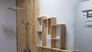Une salle de bain avec un meuble-lavabo en bois, un lavabo blanc, des toilettes et une douche.