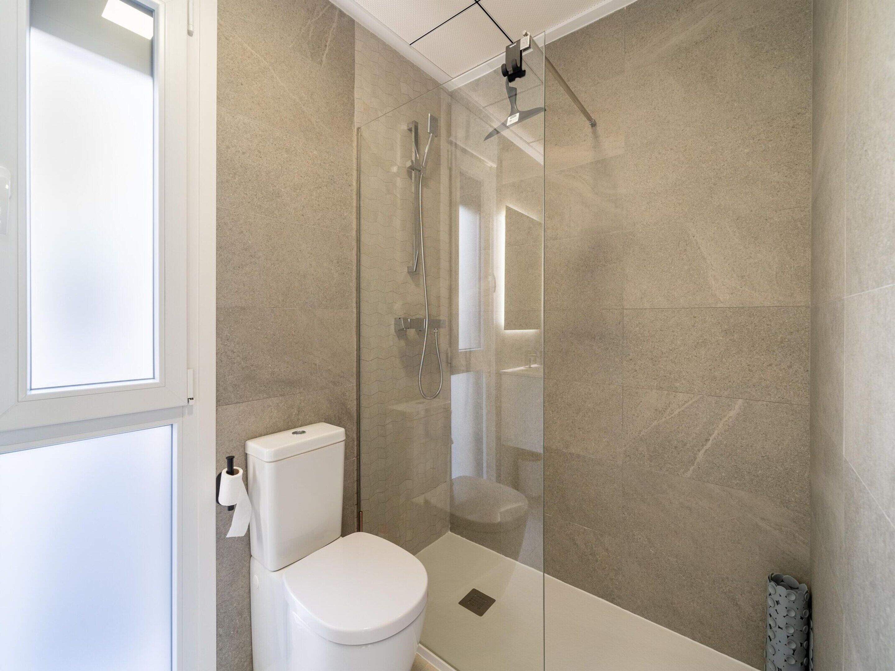 A modern bathroom with a glass-enclosed shower, a toilet, and a sink.