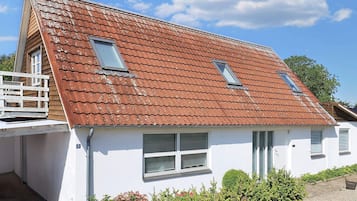 A two-story house with a sloped roof, white exterior walls, and a small porch.