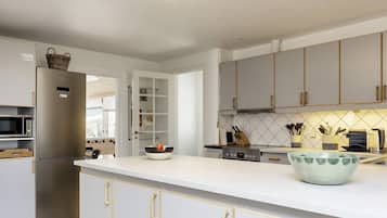 A modern kitchen with a built-in microwave, a stainless steel refrigerator, and a large island with a bowl.