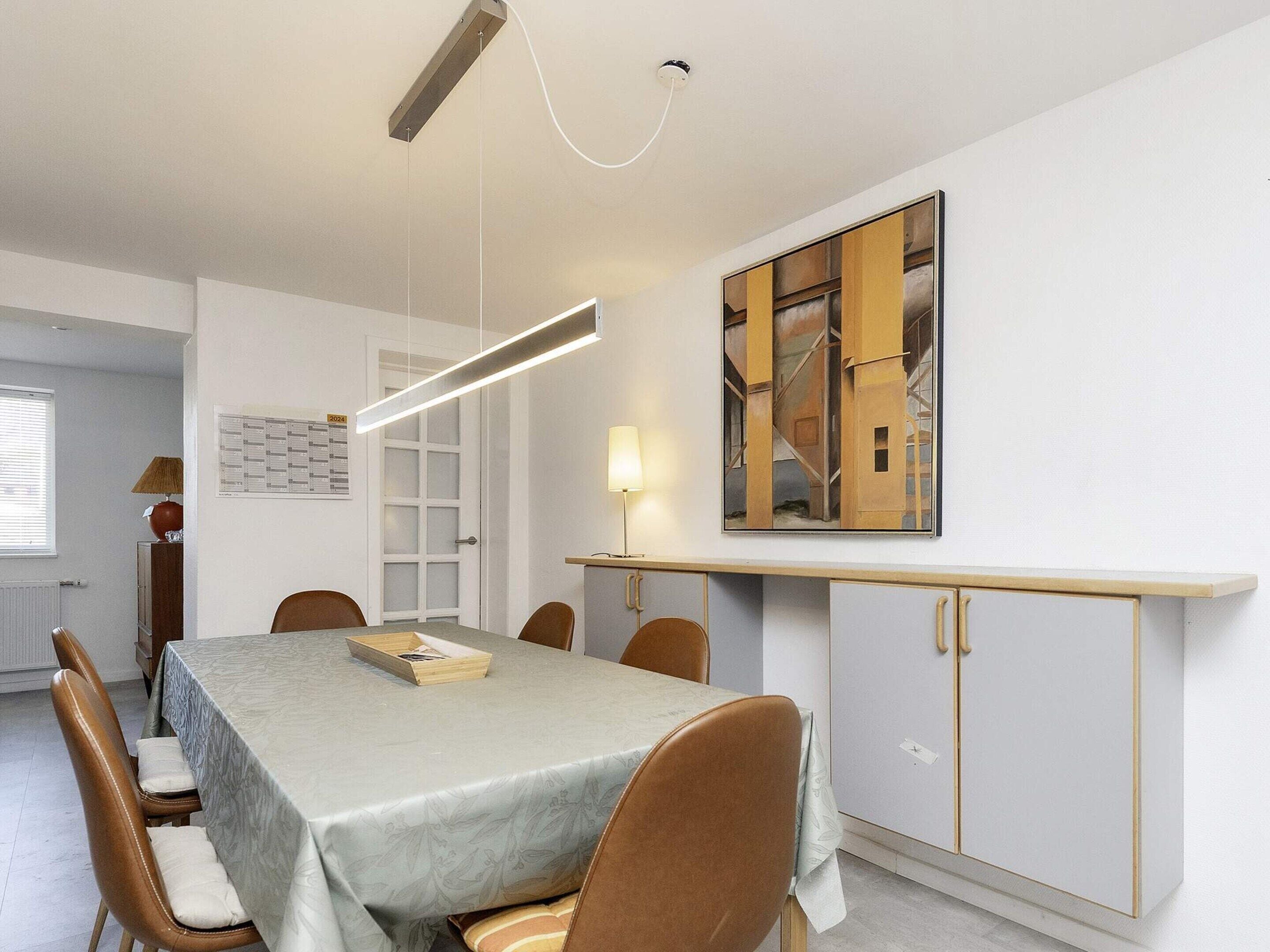 Un espace repas comprenant une table, des chaises, un buffet et un luminaire suspendu.
