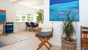 A room with a large painting, a wicker basket, and a chair.