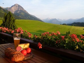 A table with food and drink, overlooking a mountainous landscape. - Holiday Apartment Rubihorn (Oberstdorf)