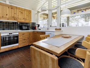 A modern kitchen with wooden cabinets, a built-in oven, and a dining area with a large table and chairs.