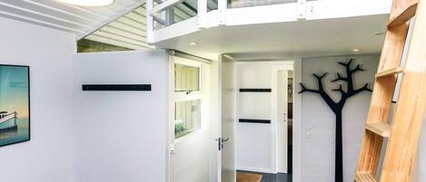 A loft bedroom with a bunk bed, a desk, and a ladder.