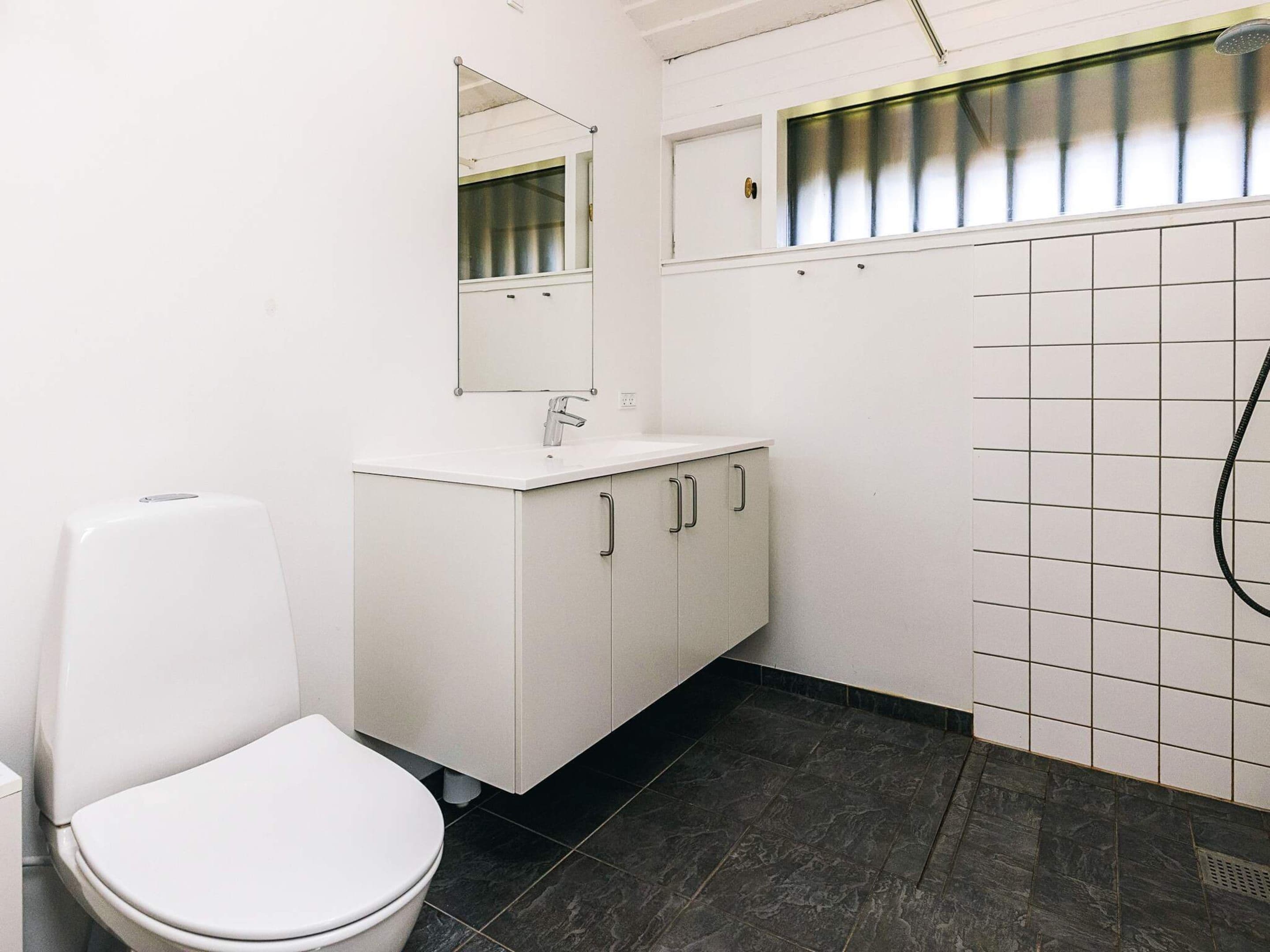 Une petite salle de bain propre, équipée de toilettes, d’un lavabo et d’un miroir.