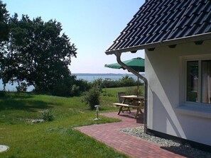 A house with a tiled roof, a brick pathway, a picnic table, and a green umbrella. - Holiday Apartment in Lancken-granitz (Rankwitz)