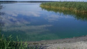 Un lac paisible aux eaux claires, où le ciel et la végétation environnante se reflètent.