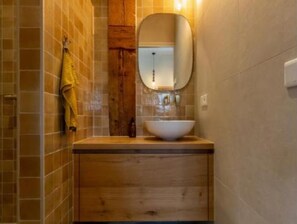 A bathroom with a wooden vanity, a white sink, and a mirror.