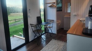 Eine moderne Küche mit einer Holz Arbeitsplatte, einem Essbereich mit Tisch und Stühlen und Blick auf eine grüne Landschaft durch die Tür.