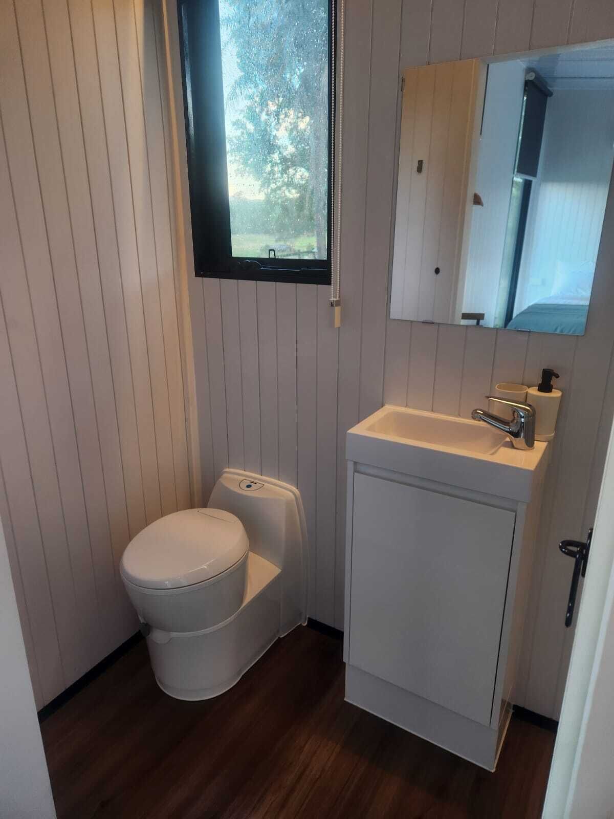 Un baño pequeño con inodoro, lavabo y espejo.