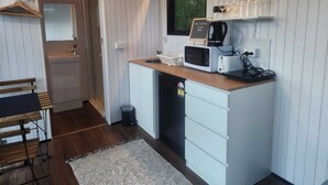 Eine kompakte Küche mit Mikrowelle, Toaster und Kaffeemaschine, einem kleinen Spülbecken und einem Fenster mit einem 'Welcome Home'-Schild.