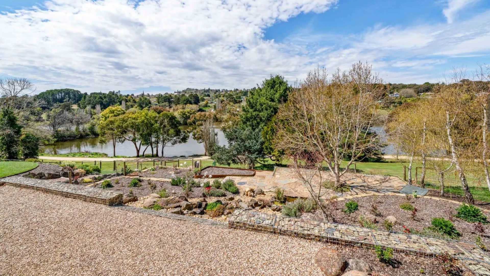 A landscaped garden with a pond, trees, and a stone pathway.