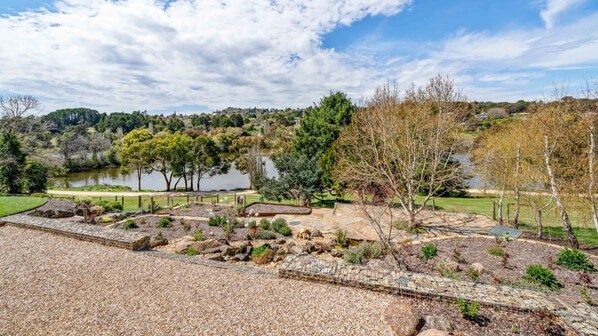 A landscaped garden with a pond, trees, and a stone pathway.
