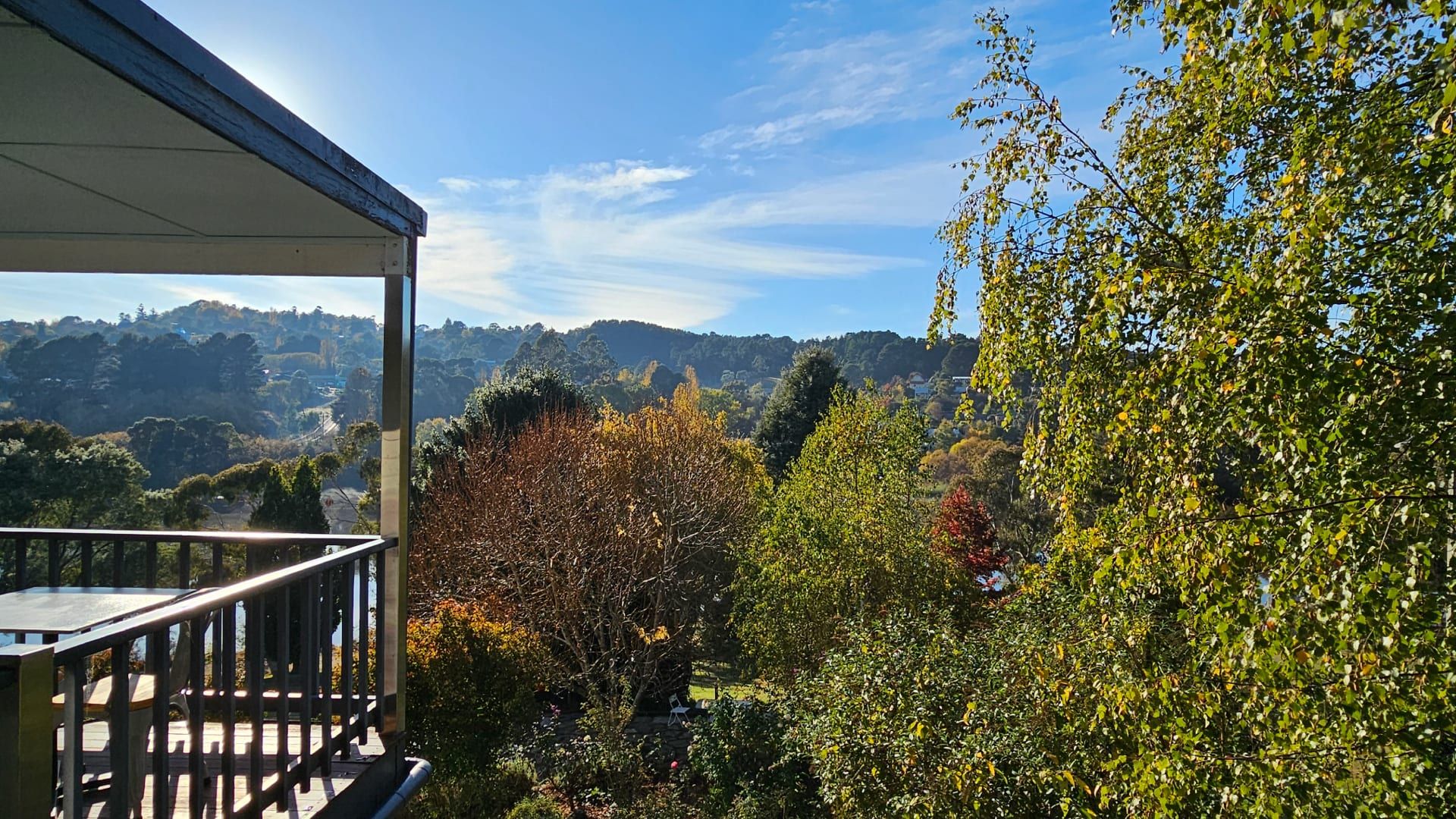 Un balcon offrant une vue sur un paysage montagneux et les couleurs automnales des arbres.