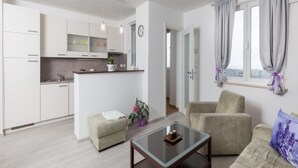 A modern apartment with a kitchen, a living area with a glass coffee table, and a sofa. - Apartment Precious View (Dubrovnik)