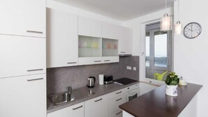 A modern kitchen with white cabinets, a dark countertop, a sink, and a window with a view. - Apartment Precious View (Dubrovnik)