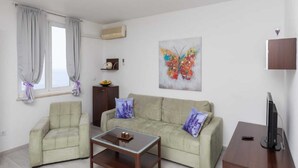 A living room with a sofa, a coffee table, a TV, and a painting on the wall. - Apartment Precious View (Dubrovnik)