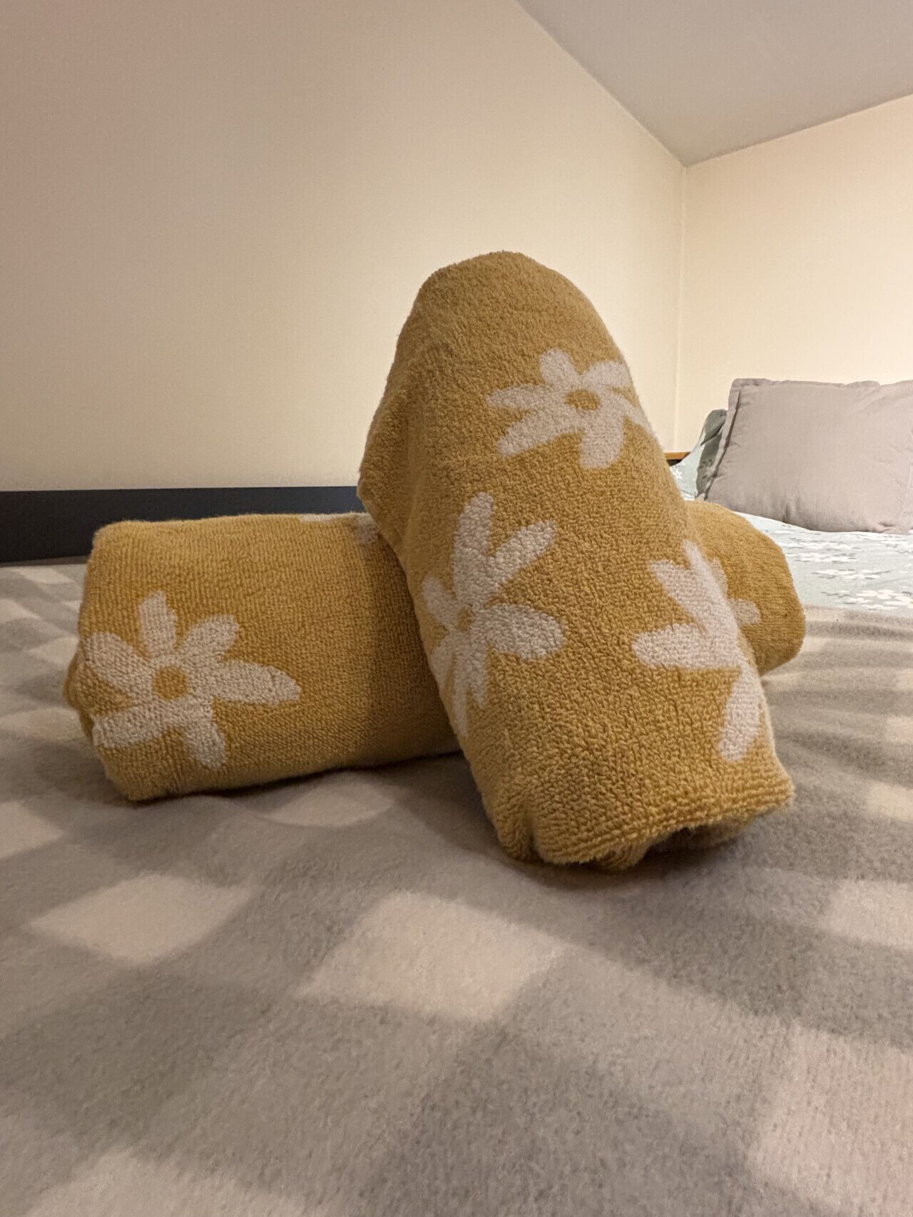 Un lit recouvert d’une couverture beige ornée d’un motif floral blanc.