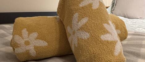 Un lit recouvert d’une couverture beige ornée d’un motif floral blanc.