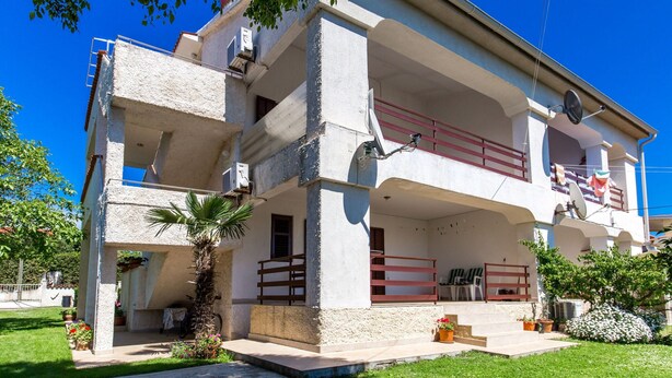 Ein zweistöckiges Gebäude mit Balkon, Außenbereich und Garten.