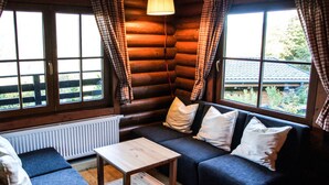 A log cabin room with a sofa, a wooden table, and plaid curtains. - Grand Wastl Comfortable Holiday Residence (Woergl)