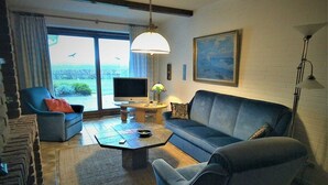 En moderne stue med sofa, lænestol og fladskærms-tv.