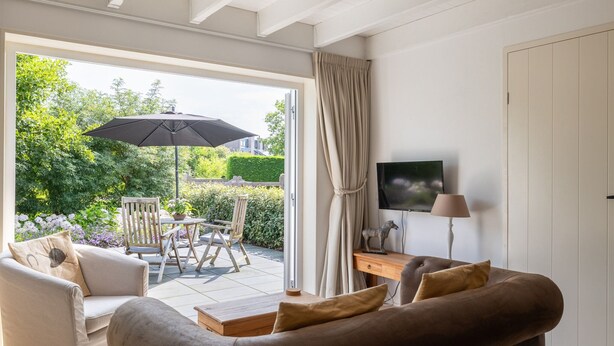 A modern living room with a sofa, a coffee table, and a TV on a stand. - Detached Retreat in Zoutelande Near Beaches (Zoutelande)