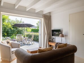 A modern living room with a sofa, a coffee table, and a TV on a stand. - Detached Retreat in Zoutelande Near Beaches (Zoutelande)