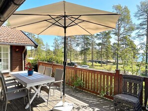 A wooden deck with a table and chairs, a large umbrella, and a view of the surrounding landscape. - 5 Person Holiday Home in Gunnebo (Gunnebo)