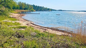 A lakeside view with a dock, calm water, and surrounding greenery. - 5 Person Holiday Home in Gunnebo (Gunnebo)