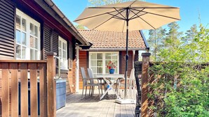 A wooden deck with a table and chairs, a large umbrella, and a potted plant. - 5 Person Holiday Home in Gunnebo (Gunnebo)